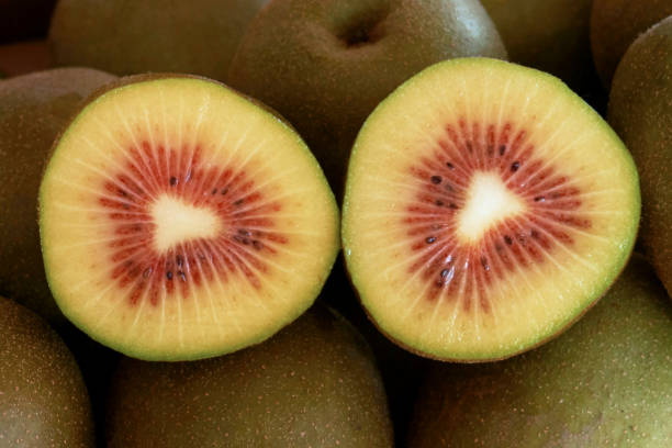 there are many kiwis piled up and one kiwi cut in half.